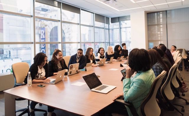 A board room with women sat round a conference table